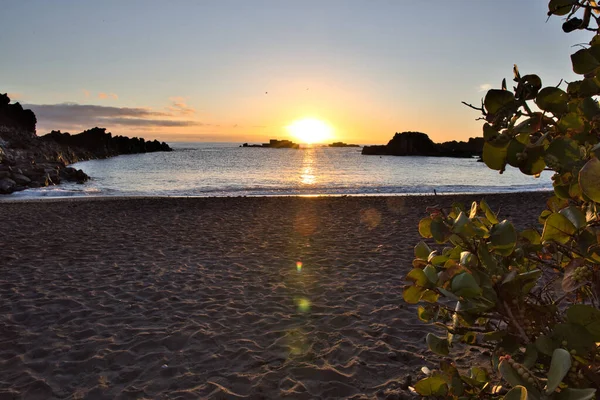 La Palma 'daki Los Cancajos' un kara kumsalında gün doğumu. Volkanik kayaların arkasında güneş patlaması var..