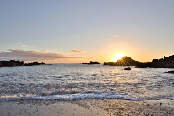 La Palma 'daki Los Cancajos' un kara kumsalında gün doğumu. Volkanik kayaların arkasında güneş patlaması var..