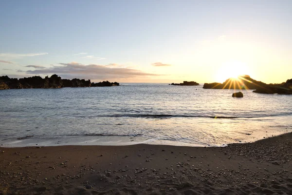 La Palma 'daki Los Cancajos' un kara kumsalında gün doğumu. Volkanik kayaların arkasında güneş patlaması var..
