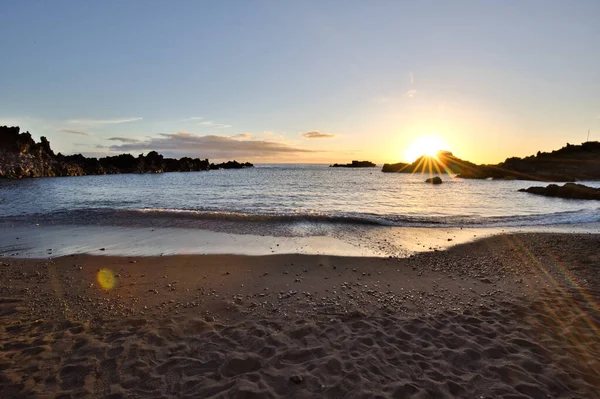 La Palma 'daki Los Cancajos' un kara kumsalında gün doğumu. Volkanik kayaların arkasında güneş patlaması var..