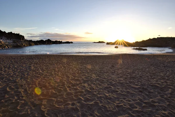 La Palma 'daki Los Cancajos' un kara kumsalında gün doğumu. Volkanik kayaların arkasında güneş patlaması var..
