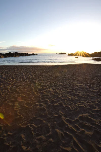 La Palma 'daki Los Cancajos' un kara kumsalında gün doğumu. Volkanik kayaların arkasında güneş patlaması var..
