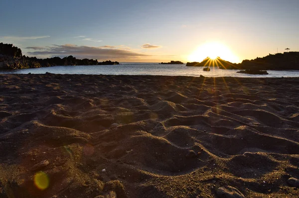 La Palma 'daki Los Cancajos' un kara kumsalında gün doğumu. Volkanik kayaların arkasında güneş patlaması var..
