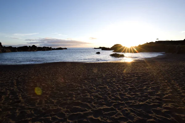 La Palma 'daki Los Cancajos' un kara kumsalında gün doğumu. Volkanik kayaların arkasında güneş patlaması var..
