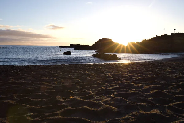 La Palma 'daki Los Cancajos' un kara kumsalında gün doğumu. Volkanik kayaların arkasında güneş patlaması var..