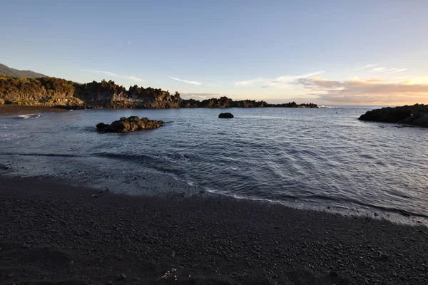 La Palma 'daki Los Cancajos' un kara kumsalında gün doğumu. Volkanik kayaların arkasında güneş patlaması var..