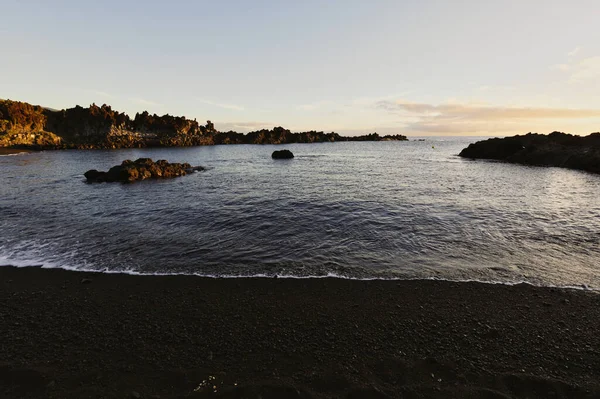La Palma 'daki Los Cancajos' un kara kumsalında gün doğumu. Volkanik kayaların arkasında güneş patlaması var..