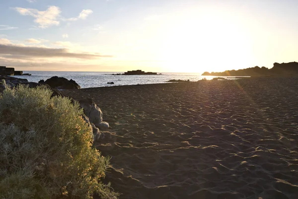 La Palma 'daki Los Cancajos' un kara kumsalında gün doğumu. Volkanik kayaların arkasında güneş patlaması var..