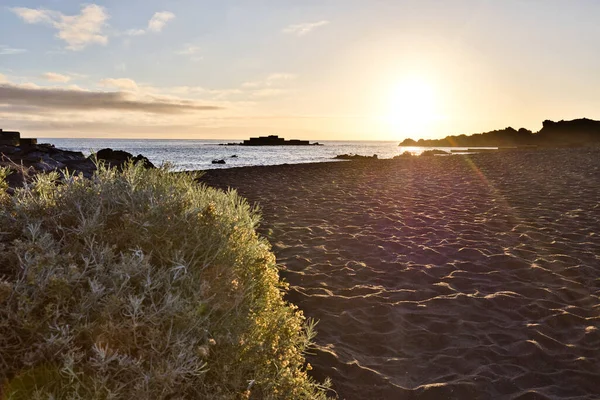 La Palma 'daki Los Cancajos' un kara kumsalında gün doğumu. Volkanik kayaların arkasında güneş patlaması var..