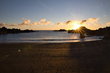 La Palma 'daki Los Cancajos' un kara kumsalında gün doğumu. Volkanik kayaların arkasında güneş patlaması var..