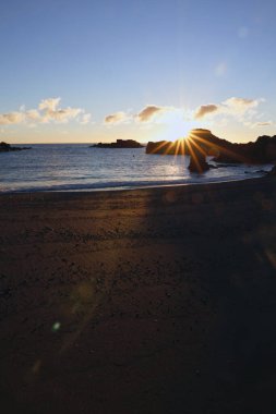 La Palma 'daki Los Cancajos' un kara kumsalında gün doğumu. Volkanik kayaların arkasında güneş patlaması var..