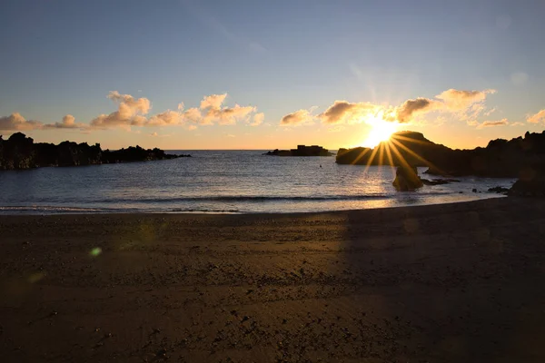 La Palma 'daki Los Cancajos' un kara kumsalında gün doğumu. Volkanik kayaların arkasında güneş patlaması var..
