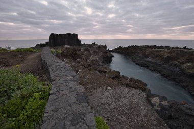 Los Cancajos, La Palma 'nın dramatik volkanik kıyı şeridi. Kara bazalt kaya oluşumları kasvetli bir gökyüzünün altında Atlantik Okyanusu ile buluşur. Kanarya Adalarında Manzaralı Seyahat