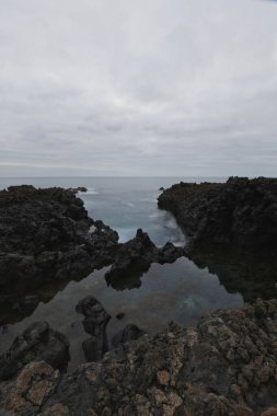 Los Cancajos, La Palma 'nın dramatik volkanik kıyı şeridi. Kara bazalt kaya oluşumları kasvetli bir gökyüzünün altında Atlantik Okyanusu ile buluşur. Kanarya Adalarında Manzaralı Seyahat