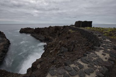 Los Cancajos, La Palma 'nın dramatik volkanik kıyı şeridi. Kara bazalt kaya oluşumları kasvetli bir gökyüzünün altında Atlantik Okyanusu ile buluşur. Kanarya Adalarında Manzaralı Seyahat