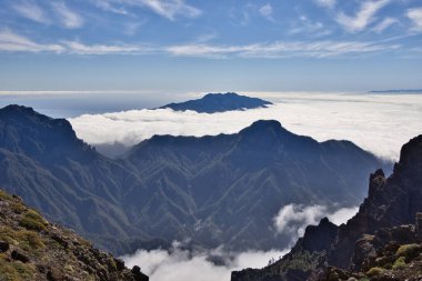 Berrak bir mavi gökyüzünün altında yoğun bir bulutlar denizinin üzerinde yükselen muhteşem bir dağ zirvesi, La Palma 'nın volkanik manzarası, Kanarya Adaları, İspanya, güzel doğa arka planı.