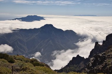 Berrak bir mavi gökyüzünün altında yoğun bir bulutlar denizinin üzerinde yükselen muhteşem bir dağ zirvesi, La Palma 'nın volkanik manzarası, Kanarya Adaları, İspanya, güzel doğa arka planı.
