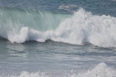 Büyük bir Atlantik dalgası Tazacorte sahiline çarpıyor. Beyaz köpük ve spreyle kırılan turkuaz suyun yakın çekimi denizin evcilleştirilmemiş gücünü gösteriyor. La Palma, Kanarya Adaları, İspanya