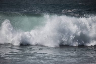 Büyük bir Atlantik dalgası Tazacorte sahiline çarpıyor. Beyaz köpük ve spreyle kırılan turkuaz suyun yakın çekimi denizin evcilleştirilmemiş gücünü gösteriyor. La Palma, Kanarya Adaları, İspanya