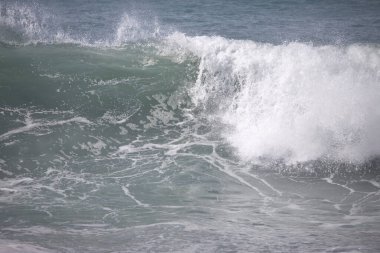 Büyük bir Atlantik dalgası Tazacorte sahiline çarpıyor. Beyaz köpük ve spreyle kırılan turkuaz suyun yakın çekimi denizin evcilleştirilmemiş gücünü gösteriyor. La Palma, Kanarya Adaları, İspanya