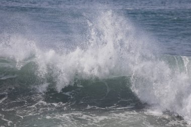 Büyük bir Atlantik dalgası Tazacorte sahiline çarpıyor. Beyaz köpük ve spreyle kırılan turkuaz suyun yakın çekimi denizin evcilleştirilmemiş gücünü gösteriyor. La Palma, Kanarya Adaları, İspanya