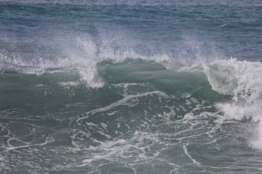 Büyük bir Atlantik dalgası Tazacorte sahiline çarpıyor. Beyaz köpük ve spreyle kırılan turkuaz suyun yakın çekimi denizin evcilleştirilmemiş gücünü gösteriyor. La Palma, Kanarya Adaları, İspanya