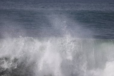 Büyük bir Atlantik dalgası Tazacorte sahiline çarpıyor. Beyaz köpük ve spreyle kırılan turkuaz suyun yakın çekimi denizin evcilleştirilmemiş gücünü gösteriyor. La Palma, Kanarya Adaları, İspanya