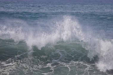 Büyük bir Atlantik dalgası Tazacorte sahiline çarpıyor. Beyaz köpük ve spreyle kırılan turkuaz suyun yakın çekimi denizin evcilleştirilmemiş gücünü gösteriyor. La Palma, Kanarya Adaları, İspanya