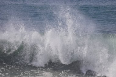 Büyük bir Atlantik dalgası Tazacorte sahiline çarpıyor. Beyaz köpük ve spreyle kırılan turkuaz suyun yakın çekimi denizin evcilleştirilmemiş gücünü gösteriyor. La Palma, Kanarya Adaları, İspanya