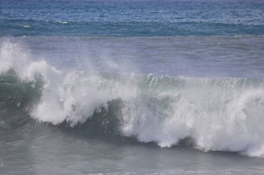Büyük bir Atlantik dalgası Tazacorte sahiline çarpıyor. Beyaz köpük ve spreyle kırılan turkuaz suyun yakın çekimi denizin evcilleştirilmemiş gücünü gösteriyor. La Palma, Kanarya Adaları, İspanya