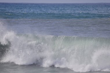 Büyük bir Atlantik dalgası Tazacorte sahiline çarpıyor. Beyaz köpük ve spreyle kırılan turkuaz suyun yakın çekimi denizin evcilleştirilmemiş gücünü gösteriyor. La Palma, Kanarya Adaları, İspanya