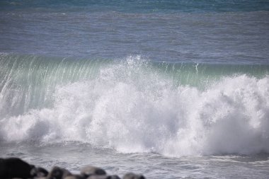 Büyük bir Atlantik dalgası Tazacorte sahiline çarpıyor. Beyaz köpük ve spreyle kırılan turkuaz suyun yakın çekimi denizin evcilleştirilmemiş gücünü gösteriyor. La Palma, Kanarya Adaları, İspanya