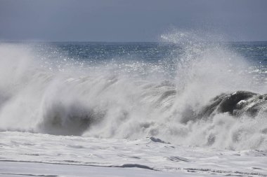 Büyük bir Atlantik dalgası Tazacorte sahiline çarpıyor. Beyaz köpük ve spreyle kırılan turkuaz suyun yakın çekimi denizin evcilleştirilmemiş gücünü gösteriyor. La Palma, Kanarya Adaları, İspanya