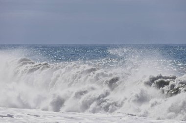 Büyük bir Atlantik dalgası Tazacorte sahiline çarpıyor. Beyaz köpük ve spreyle kırılan turkuaz suyun yakın çekimi denizin evcilleştirilmemiş gücünü gösteriyor. La Palma, Kanarya Adaları, İspanya