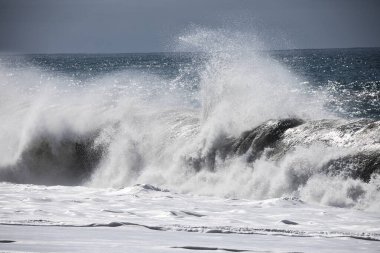 Büyük bir Atlantik dalgası Tazacorte sahiline çarpıyor. Beyaz köpük ve spreyle kırılan turkuaz suyun yakın çekimi denizin evcilleştirilmemiş gücünü gösteriyor. La Palma, Kanarya Adaları, İspanya