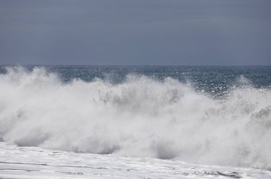 Büyük bir Atlantik dalgası Tazacorte sahiline çarpıyor. Beyaz köpük ve spreyle kırılan turkuaz suyun yakın çekimi denizin evcilleştirilmemiş gücünü gösteriyor. La Palma, Kanarya Adaları, İspanya