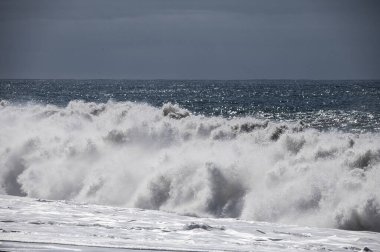 Büyük bir Atlantik dalgası Tazacorte sahiline çarpıyor. Beyaz köpük ve spreyle kırılan turkuaz suyun yakın çekimi denizin evcilleştirilmemiş gücünü gösteriyor. La Palma, Kanarya Adaları, İspanya