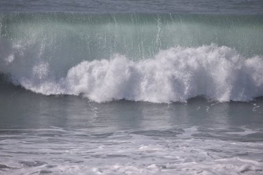 Büyük bir Atlantik dalgası Tazacorte sahiline çarpıyor. Beyaz köpük ve spreyle kırılan turkuaz suyun yakın çekimi denizin evcilleştirilmemiş gücünü gösteriyor. La Palma, Kanarya Adaları, İspanya