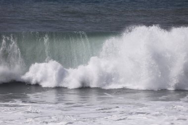 Büyük bir Atlantik dalgası Tazacorte sahiline çarpıyor. Beyaz köpük ve spreyle kırılan turkuaz suyun yakın çekimi denizin evcilleştirilmemiş gücünü gösteriyor. La Palma, Kanarya Adaları, İspanya