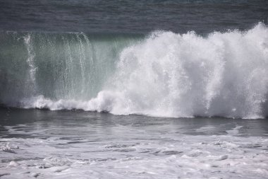 Büyük bir Atlantik dalgası Tazacorte sahiline çarpıyor. Beyaz köpük ve spreyle kırılan turkuaz suyun yakın çekimi denizin evcilleştirilmemiş gücünü gösteriyor. La Palma, Kanarya Adaları, İspanya