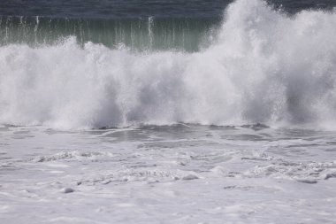 Büyük bir Atlantik dalgası Tazacorte sahiline çarpıyor. Beyaz köpük ve spreyle kırılan turkuaz suyun yakın çekimi denizin evcilleştirilmemiş gücünü gösteriyor. La Palma, Kanarya Adaları, İspanya