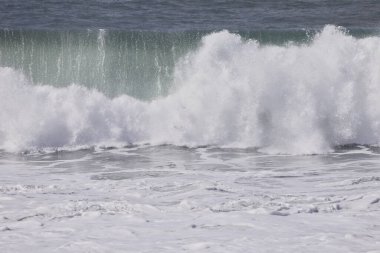 Büyük bir Atlantik dalgası Tazacorte sahiline çarpıyor. Beyaz köpük ve spreyle kırılan turkuaz suyun yakın çekimi denizin evcilleştirilmemiş gücünü gösteriyor. La Palma, Kanarya Adaları, İspanya