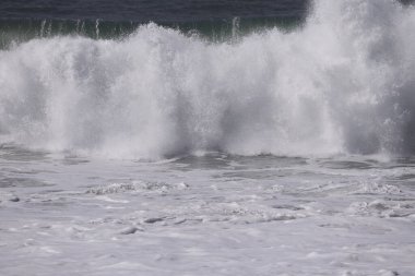 Büyük bir Atlantik dalgası Tazacorte sahiline çarpıyor. Beyaz köpük ve spreyle kırılan turkuaz suyun yakın çekimi denizin evcilleştirilmemiş gücünü gösteriyor. La Palma, Kanarya Adaları, İspanya