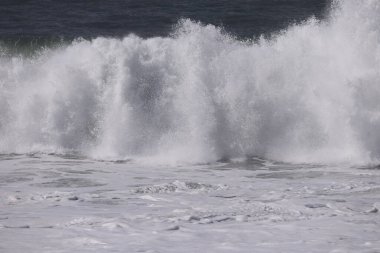 Büyük bir Atlantik dalgası Tazacorte sahiline çarpıyor. Beyaz köpük ve spreyle kırılan turkuaz suyun yakın çekimi denizin evcilleştirilmemiş gücünü gösteriyor. La Palma, Kanarya Adaları, İspanya