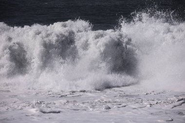 Büyük bir Atlantik dalgası Tazacorte sahiline çarpıyor. Beyaz köpük ve spreyle kırılan turkuaz suyun yakın çekimi denizin evcilleştirilmemiş gücünü gösteriyor. La Palma, Kanarya Adaları, İspanya