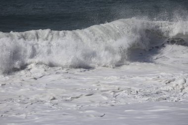 Büyük bir Atlantik dalgası Tazacorte sahiline çarpıyor. Beyaz köpük ve spreyle kırılan turkuaz suyun yakın çekimi denizin evcilleştirilmemiş gücünü gösteriyor. La Palma, Kanarya Adaları, İspanya