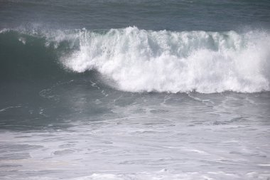 Büyük bir Atlantik dalgası Tazacorte sahiline çarpıyor. Beyaz köpük ve spreyle kırılan turkuaz suyun yakın çekimi denizin evcilleştirilmemiş gücünü gösteriyor. La Palma, Kanarya Adaları, İspanya