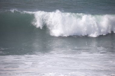 Büyük bir Atlantik dalgası Tazacorte sahiline çarpıyor. Beyaz köpük ve spreyle kırılan turkuaz suyun yakın çekimi denizin evcilleştirilmemiş gücünü gösteriyor. La Palma, Kanarya Adaları, İspanya