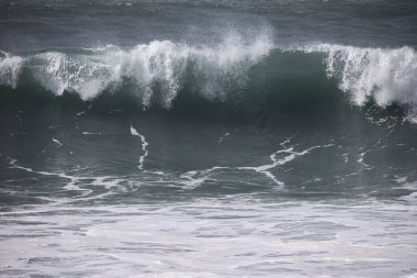 Büyük bir Atlantik dalgası Tazacorte sahiline çarpıyor. Beyaz köpük ve spreyle kırılan turkuaz suyun yakın çekimi denizin evcilleştirilmemiş gücünü gösteriyor. La Palma, Kanarya Adaları, İspanya