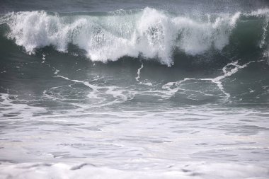 Büyük bir Atlantik dalgası Tazacorte sahiline çarpıyor. Beyaz köpük ve spreyle kırılan turkuaz suyun yakın çekimi denizin evcilleştirilmemiş gücünü gösteriyor. La Palma, Kanarya Adaları, İspanya